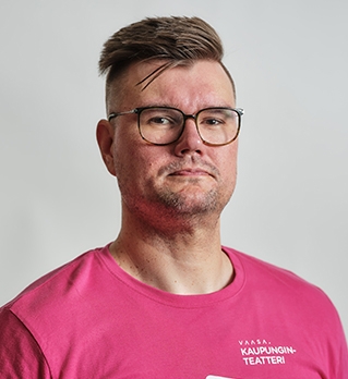 Teemu Vähänen katsoo kameraan, pinkissä paidassa Vaasan kaupunginteatterin logo.