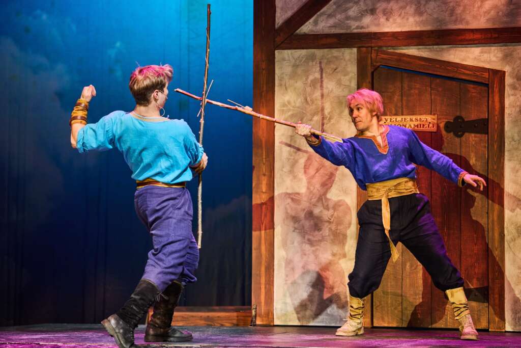 Kaksi henkilöä miekkailee kepeillä, taustalla ovi. Esityskuva Veljeni, Leijonamieli -näytelmästä.