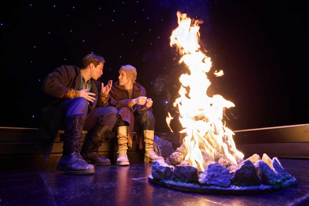 Kaksi henkilöä katsovat toisiaan nuotion ääressä. Esityskuva Veljeni, Leijonamieli -näytelmästä.