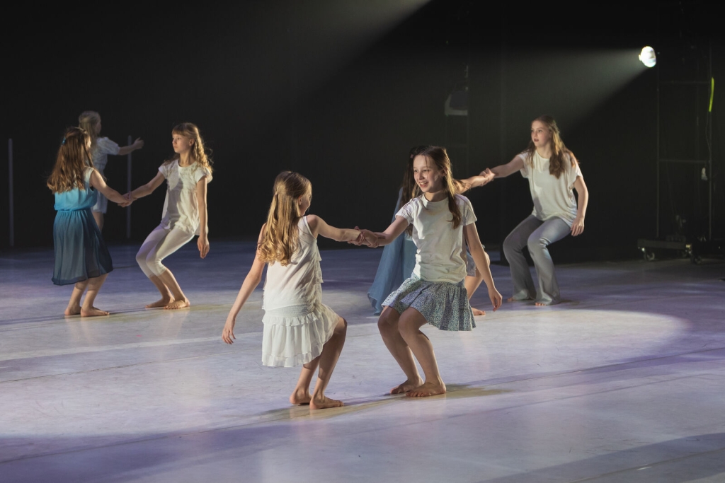 Barnen dansar i par. De håller varandra i handen och lutar sig bakåt.