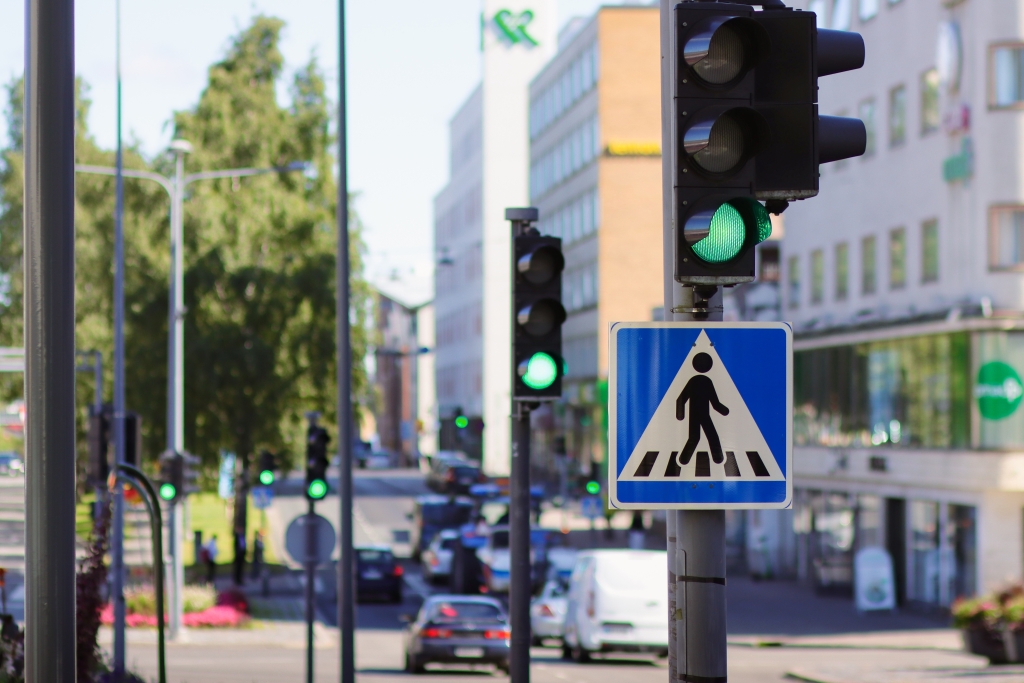 The traffic light is green, with a city street and cars in the background.