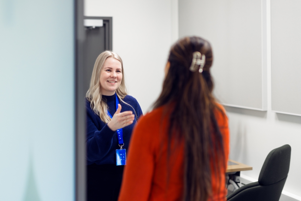A woman greets another woman in the doorway.