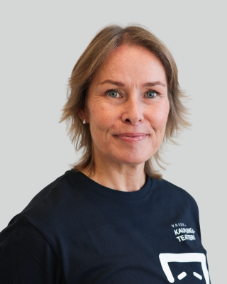 Kaisa Wegelius hymyilee ja katsoo kameraan, päällä sininen paita.