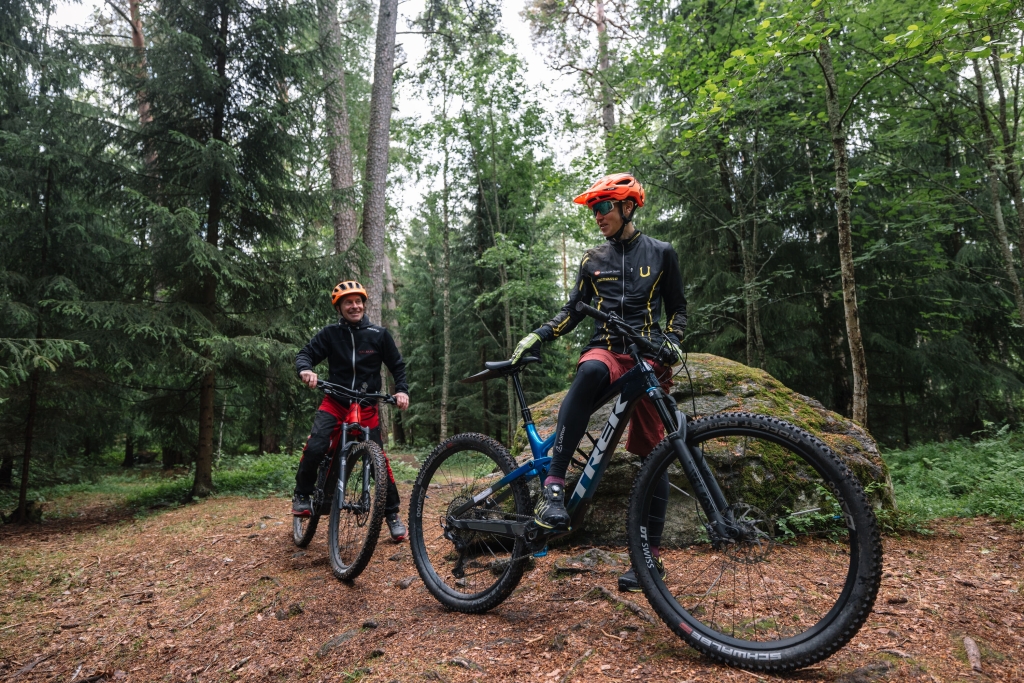 Två mountainbikecyklister har stannat till på en skogsstig för att prata.