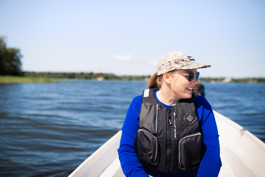 Person sitting on a boat wearing sunglasses and a cap.