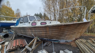 Vanha puuvene maalla, taustalla syksyisiä puita.