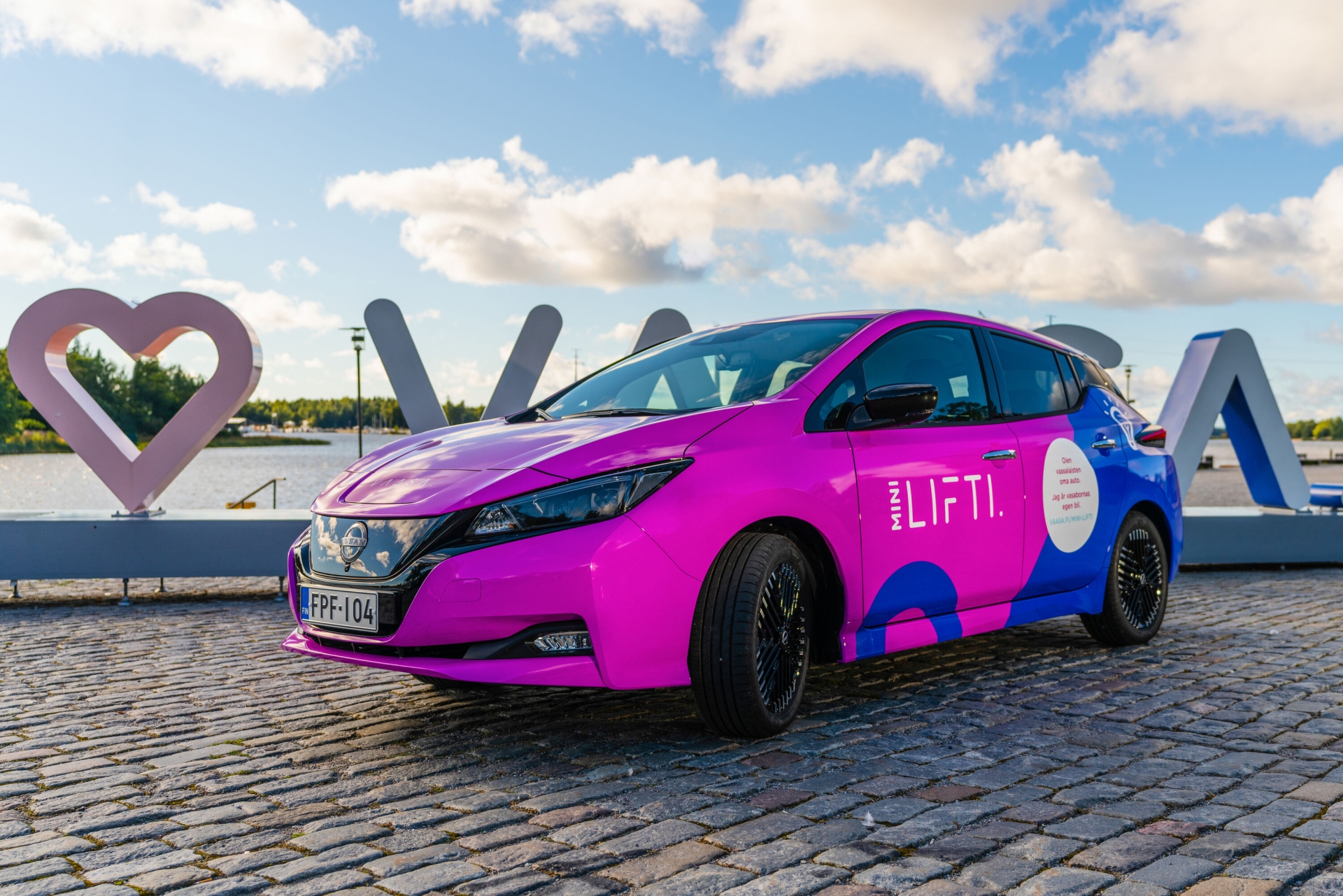 Violetti Mini-Lifti sähköauto merimaiseman edessä.