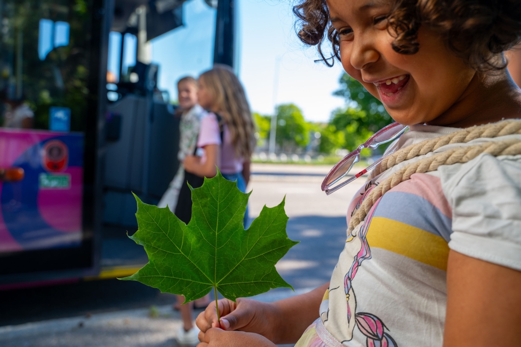 lapsi seisoo kadulla puunlehden kanssa.