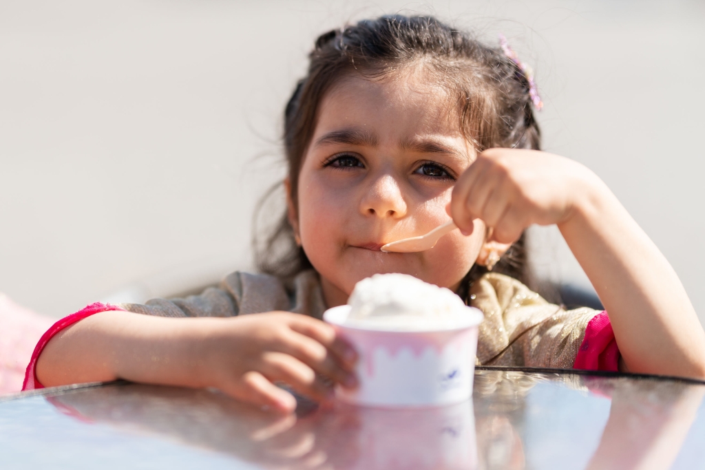 Pieni tyttö syö jäätelöä kupista.