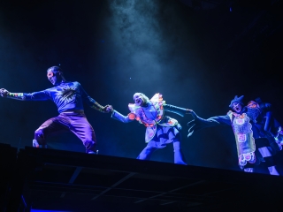 Kolme henkilöä näyttämöllä peräkkäin innostuneet ilmeet kasvoillaan, pitelevät toisiaan kädestä kiinni, esityskuva Aladdin ja taikalamppu -näytelmästä.