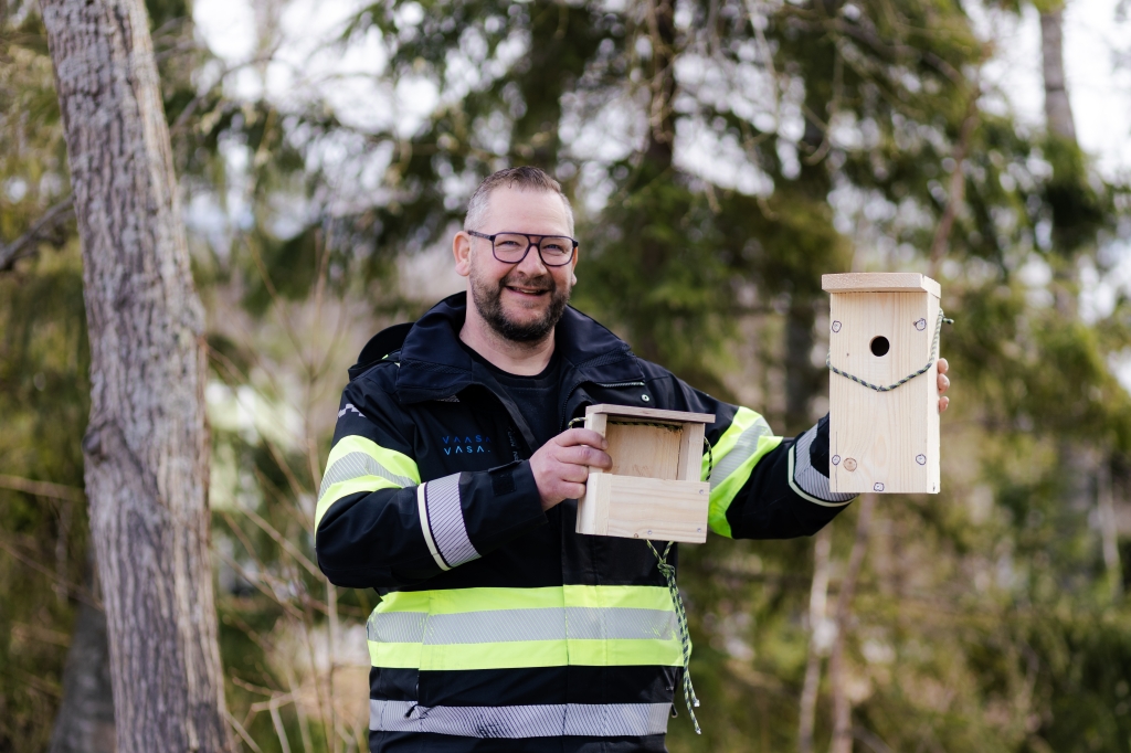 Henkilö pitää kädessään kahta linnunpönttöä ulkona metsässä.
