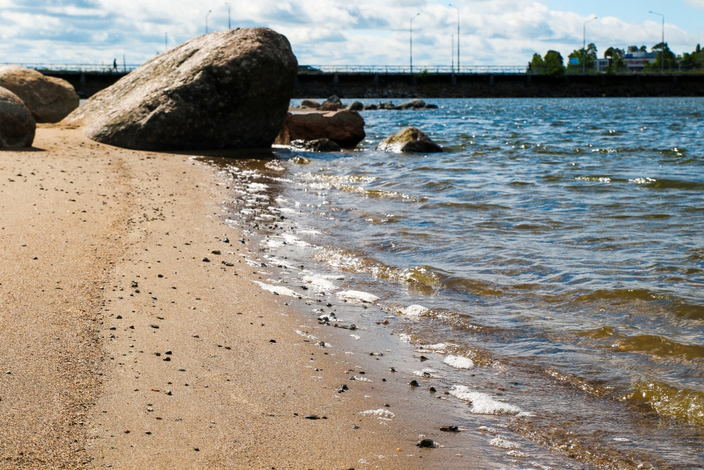 A beach that has a bridge in the backround on a sunny day.