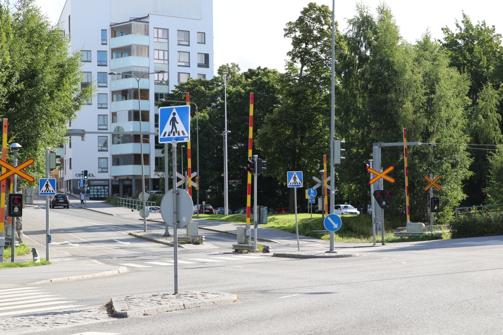 Plankorsningen vid Verkstadsgatan med trafiksignaler, järnvägsbommar och vägskyltar.