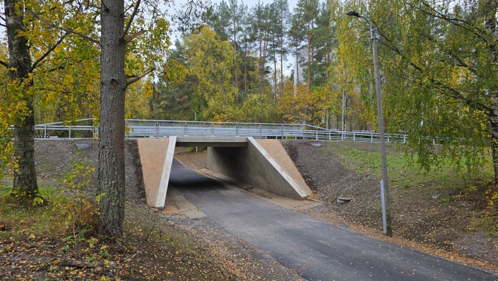Pyörätie kulkee pienen betonisillan alitse syksyisessä maisemassa.