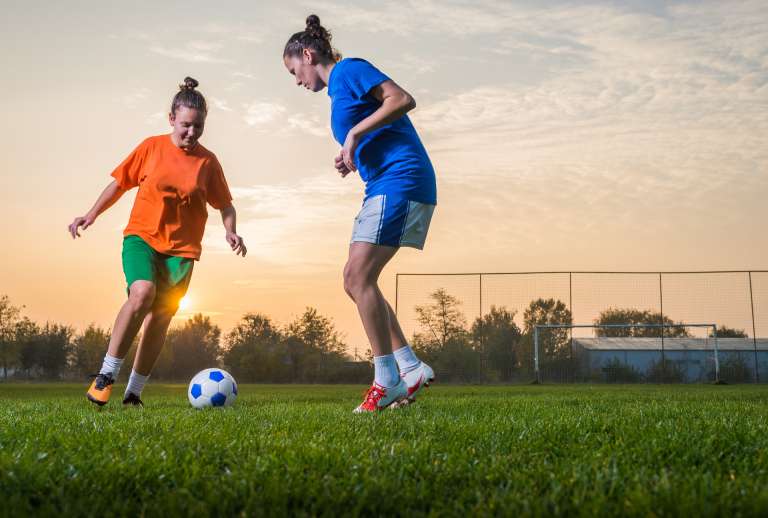 Kaksi tyttöä pelaa jalkapalloa