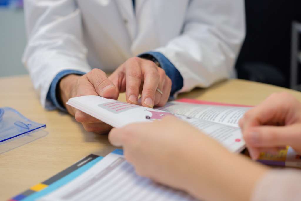 Läkare ger broschyr till patient.