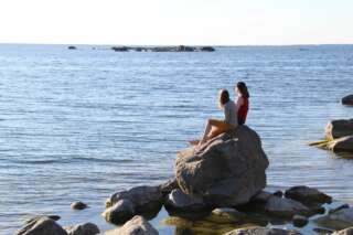 Människor sitter på en sten vid vattnet