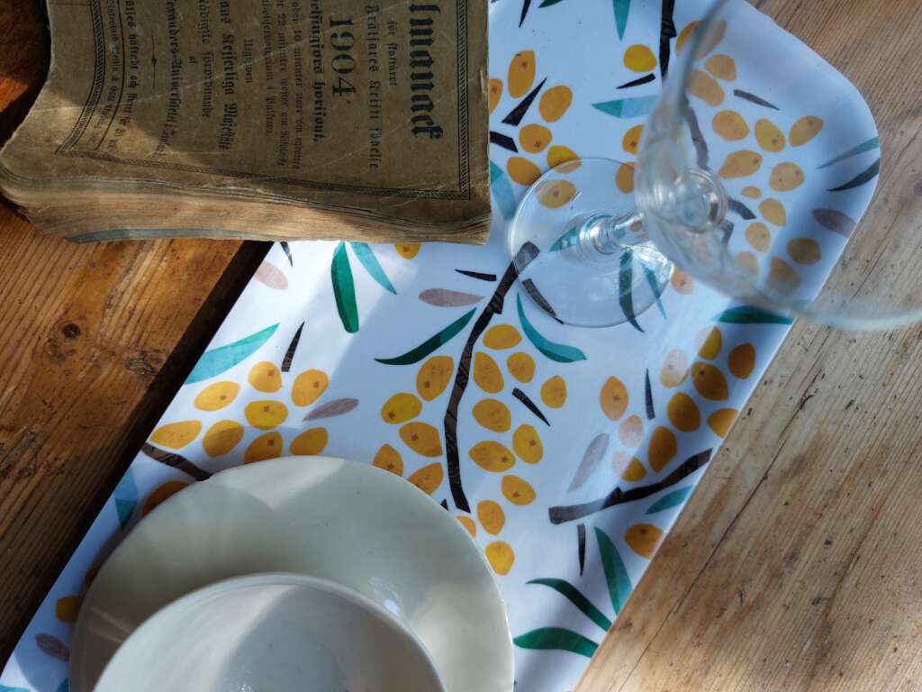 A tray pf plywood, a glass, a coffee cup and an old book.