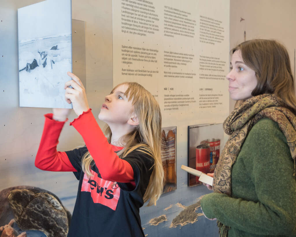 A child and an adult are reading a sign in an exhibition.