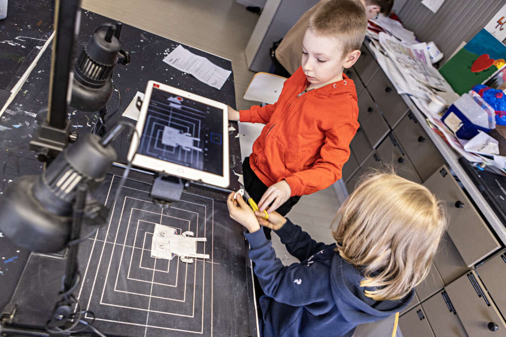 Kaksi lasta tekevät luokkahuoneessa paperihahmoanimaatiota ipadin avulla.