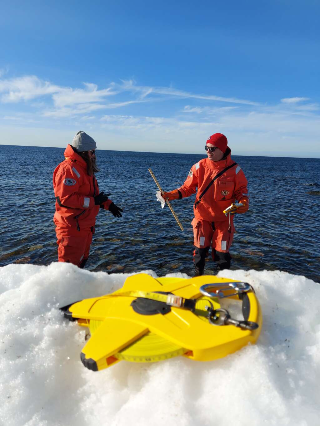 Två män i överlevnadsdräkter vid havet