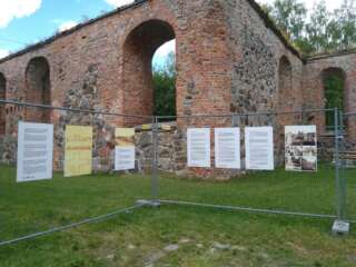 Utställningsskyltar fästa i en skyddande asida. I bakgrunden syns ruinerna av Gamla Vasa.