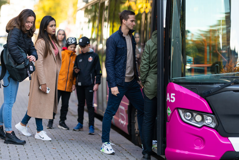 Ihmisiä kävelemässä bussiin.