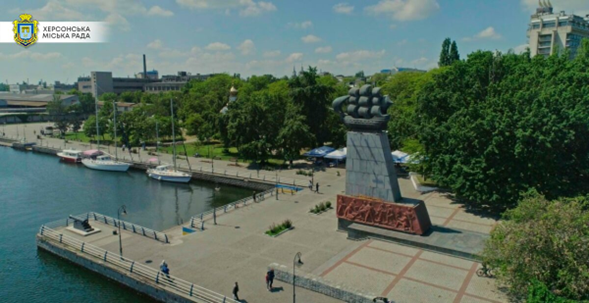 A pier at a river with a statue of a sailing ship.