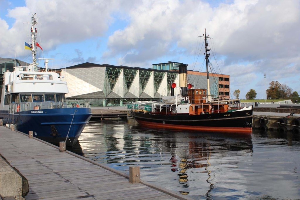A harbour with two boats and the cultural centre in the background.