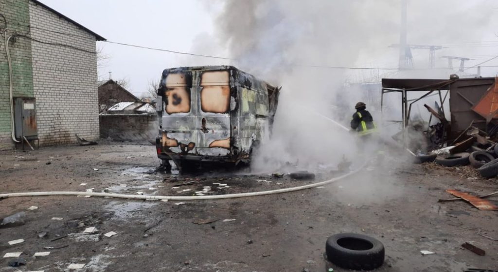 A firefighter is distinguishing a burning van.