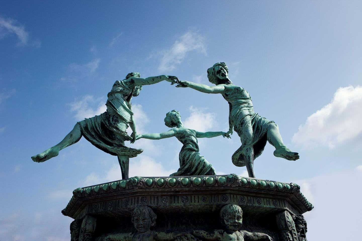 Three bronze figures depicting dancing women.