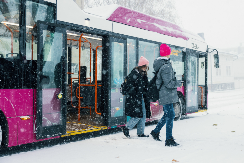 Kaksi ihmistä poistumassa Liftin bussista lumisateessa.