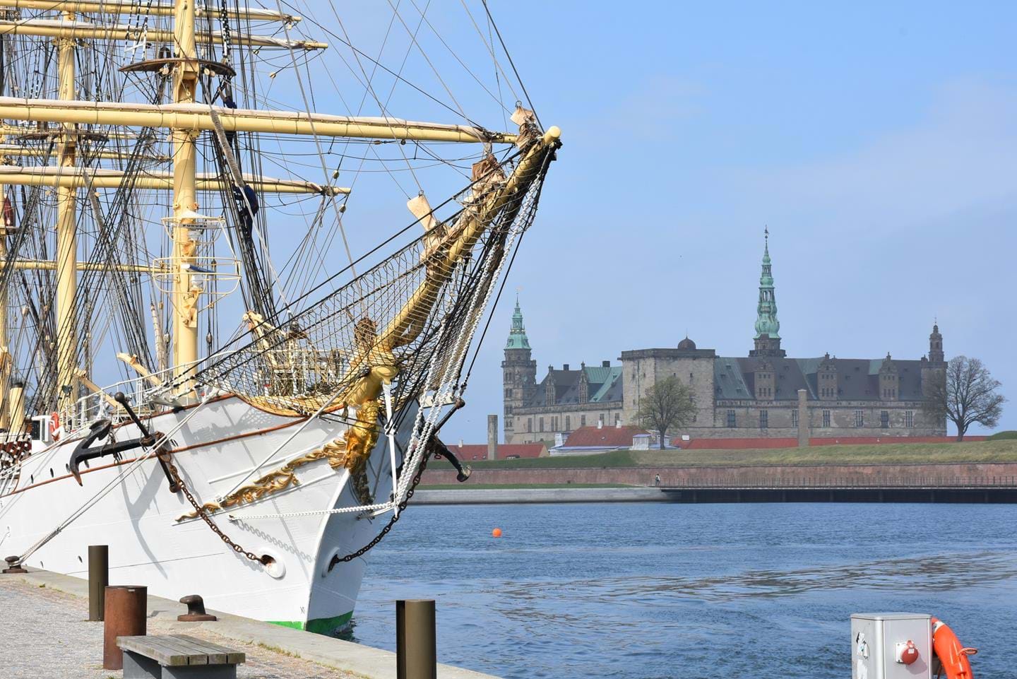 An old sailing ship with a castle in the background.