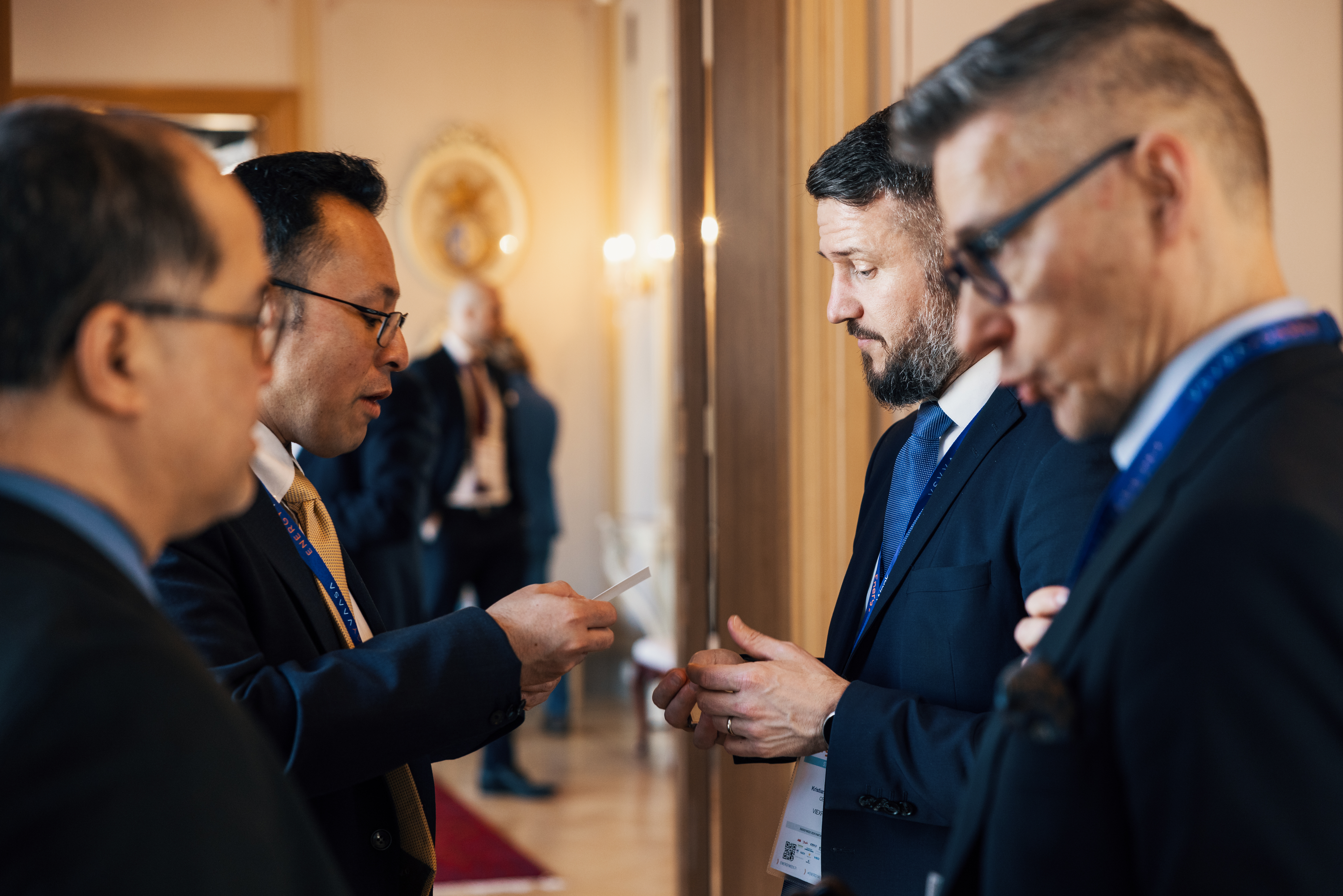 Four men talking with each other. One is handing his business card to another.